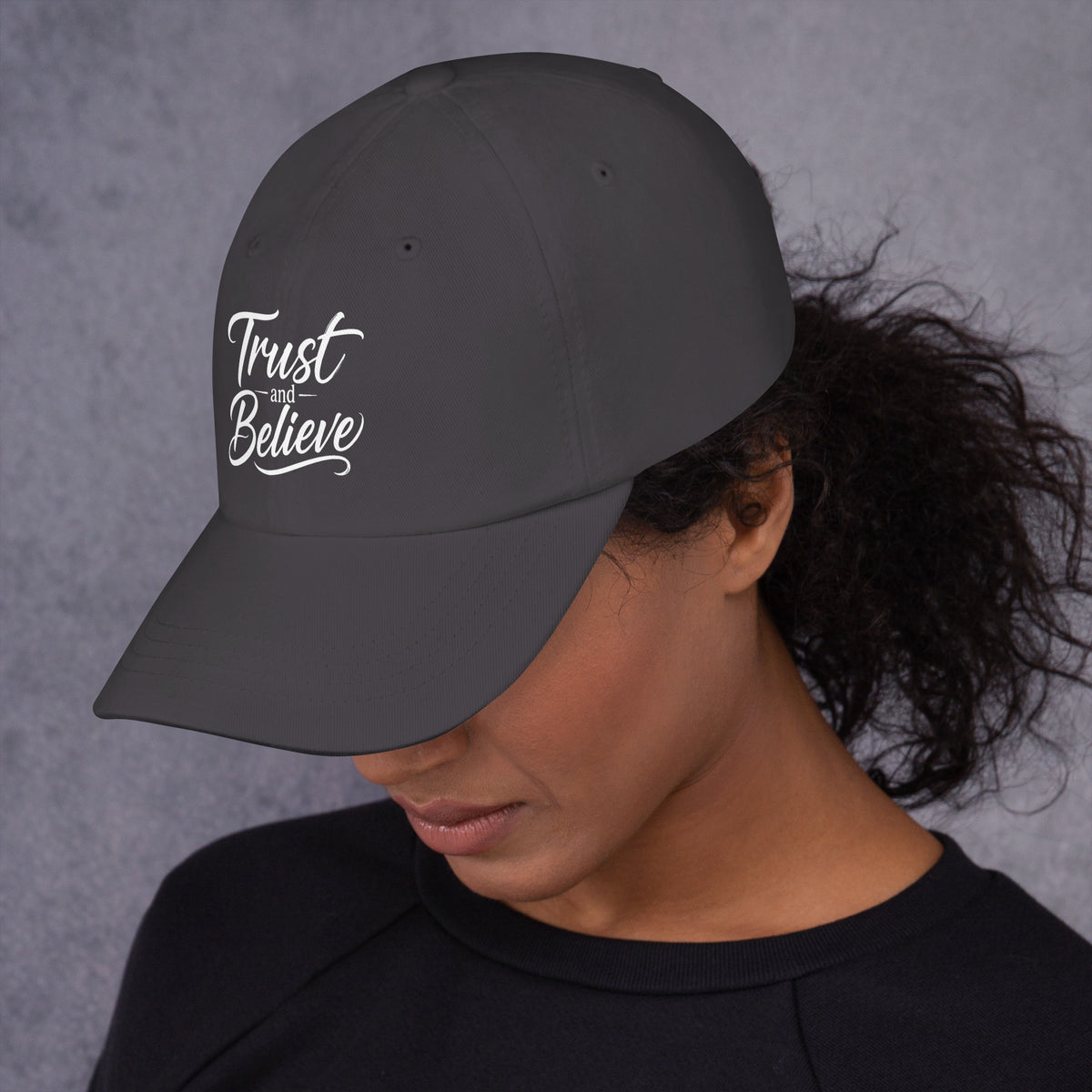 Trust and Believe design, on a dark grey dad hat, left side view