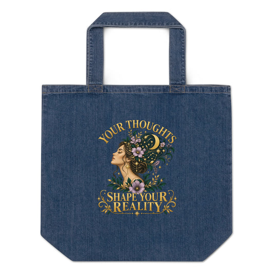 Your Thoughts Shape Your Reality organic denim tote bag in denim blue, front. Gold lettering above a woman's profile with her thoughts becoming stars and lavender.