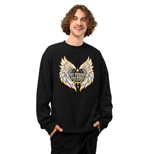 My Person Has Wings In Heaven design, gold and white angel wings curving into a heart around gold lettering with blue star sparkles, on a black oversized heavyweight sweatshirt worn by a model, front view