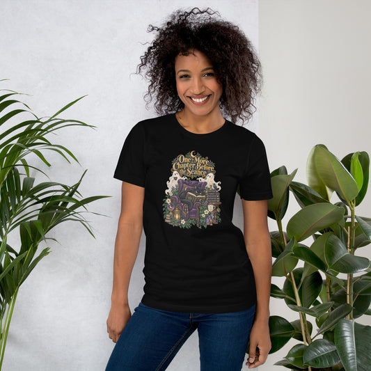 One More Chapter Before The Séance dark academia design, a black cat reading in a velvet armchair with two ghosts, on a black unisex t-shirt, front view