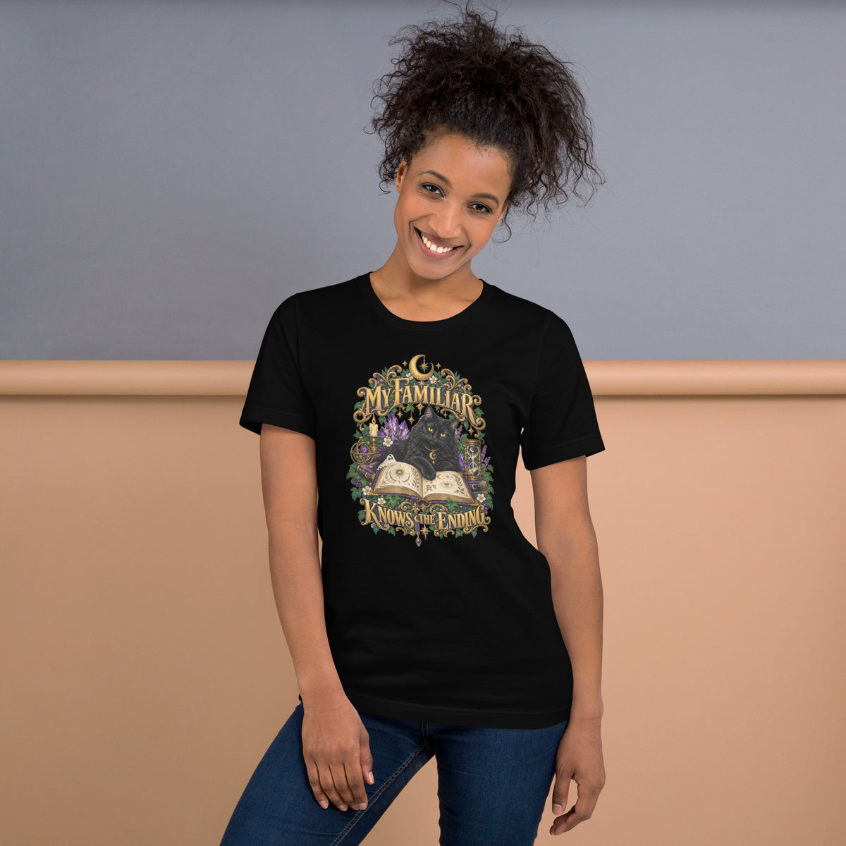 Black cat familiar on a grimoire, witchy celestial design on a black unisex t-shirt, front view