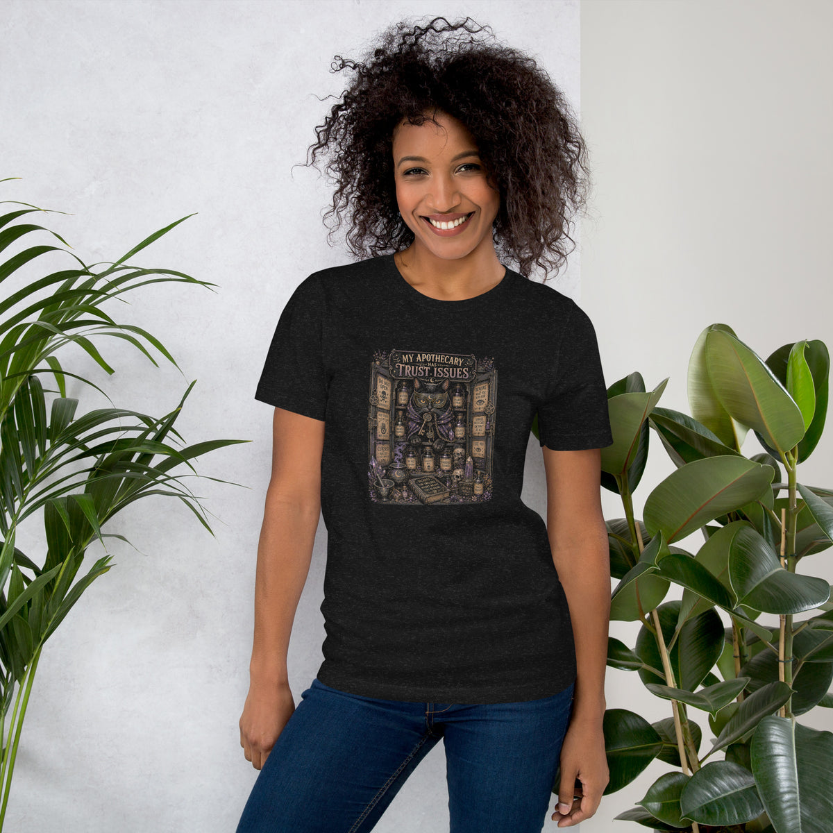 My Apothecary Has Trust Issues, a witchy black cat and a cabinet of potion bottles, on a black heather unisex t-shirt, front view