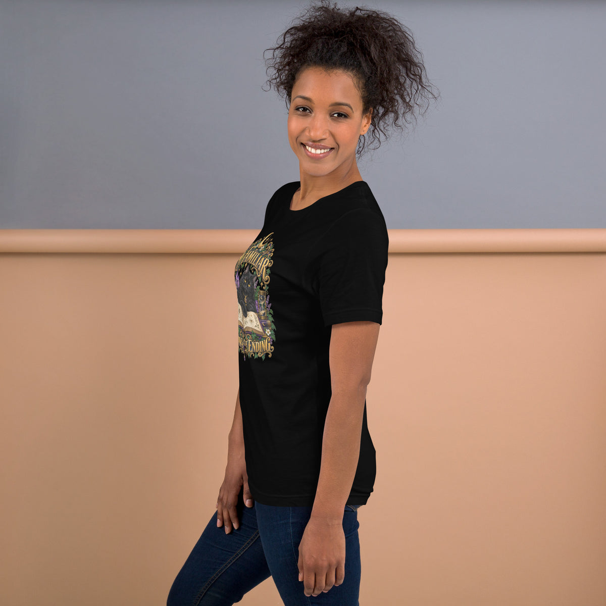 Black cat familiar on a grimoire, witchy celestial design on a black unisex t-shirt, left side