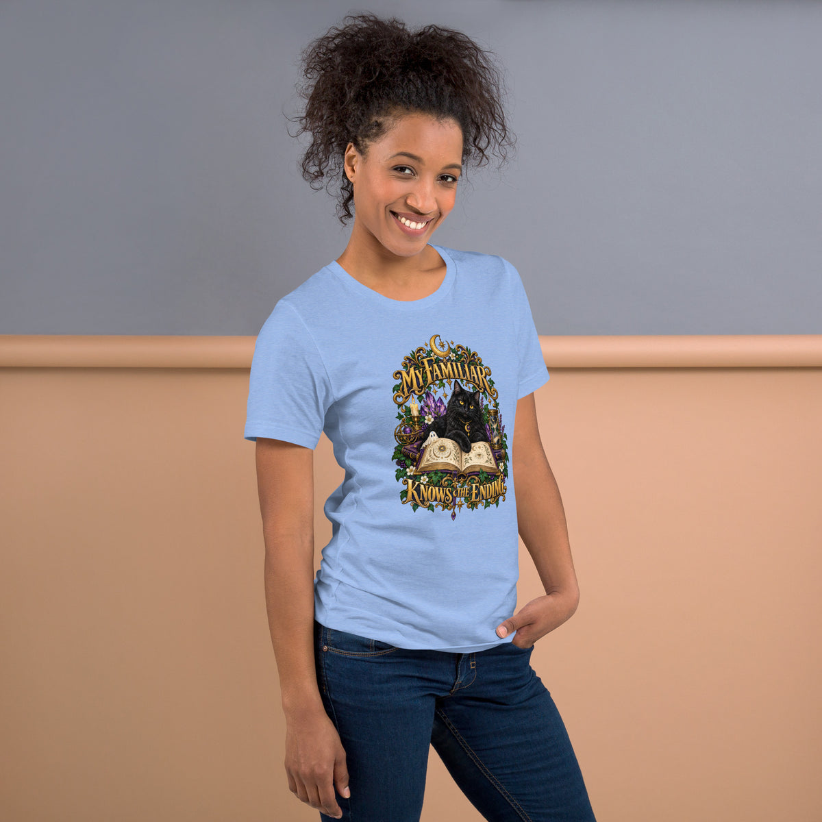 Black cat familiar on a grimoire, witchy celestial design on a heather carolina blue t-shirt, right side