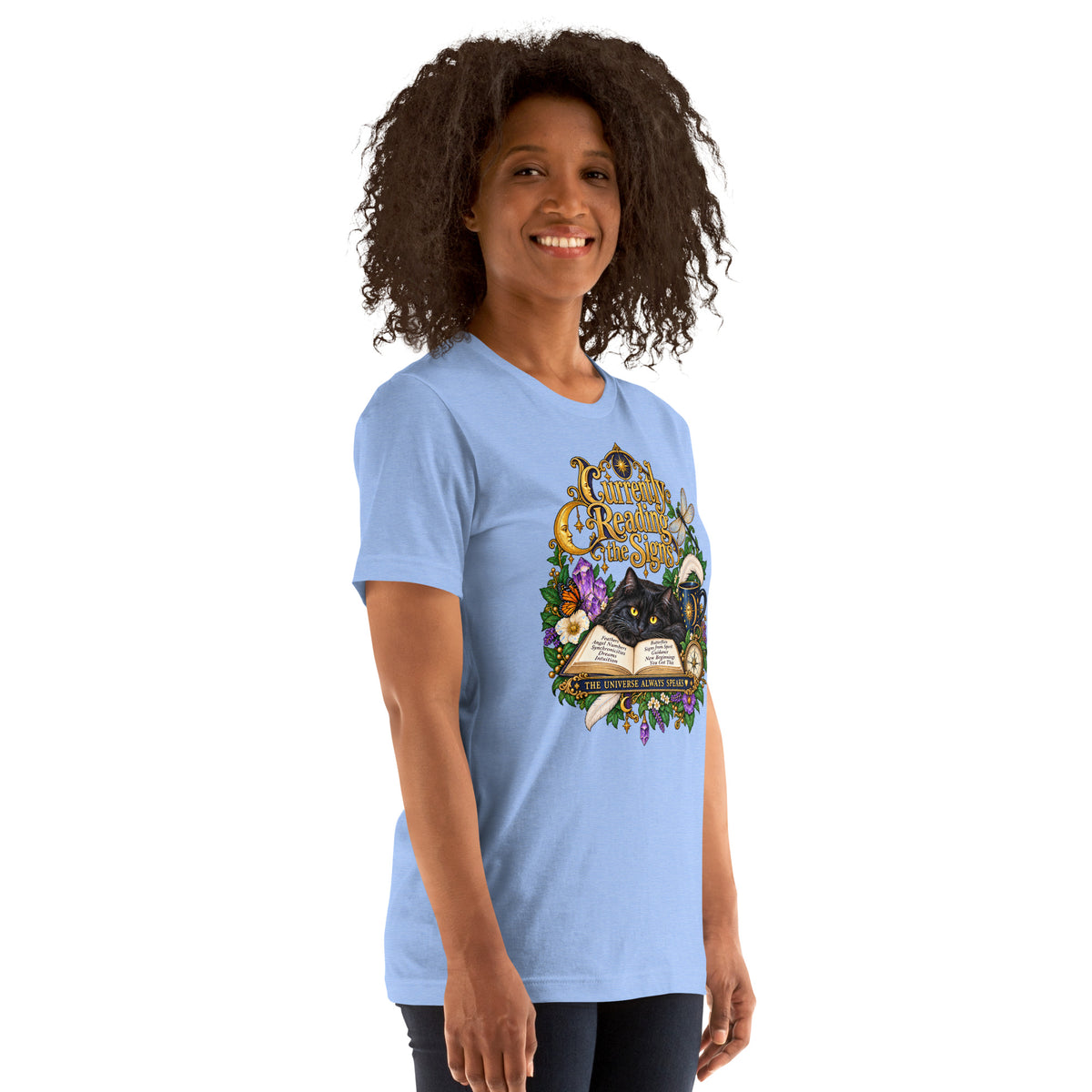 Currently Reading The Signs dark academia design, two black cats asleep over an open book beneath a crescent moon, on a heather carolina blue unisex t-shirt, right front view