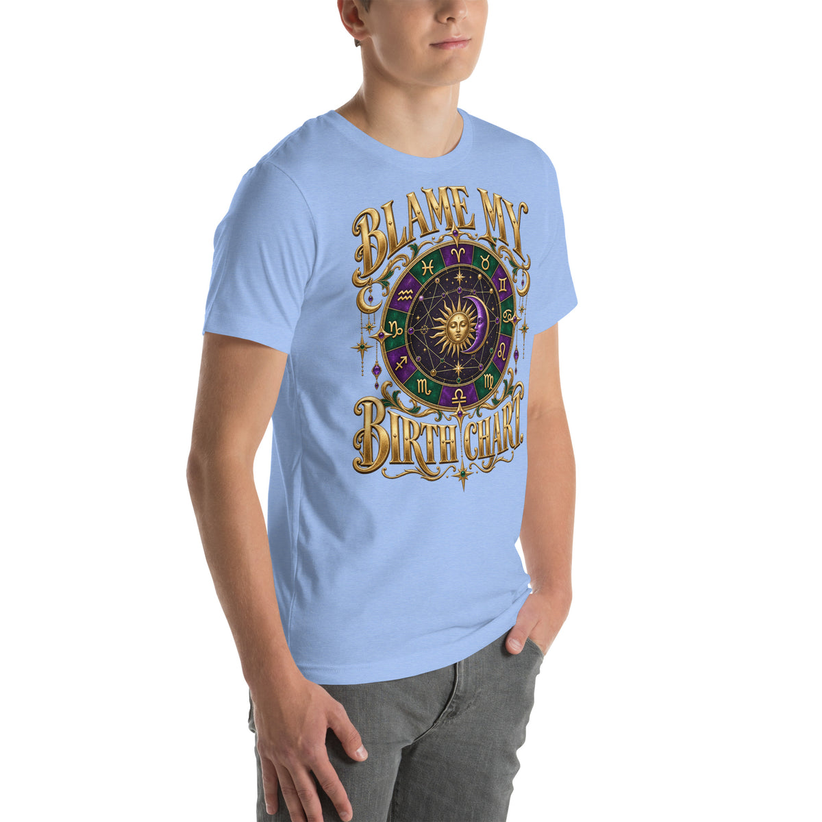 Blame My Birth Chart astrology design, a purple and green zodiac wheel with a gold sun face and crescent moon at its center, hung with gold ornaments, on a heather carolina blue unisex t-shirt, angled right front view