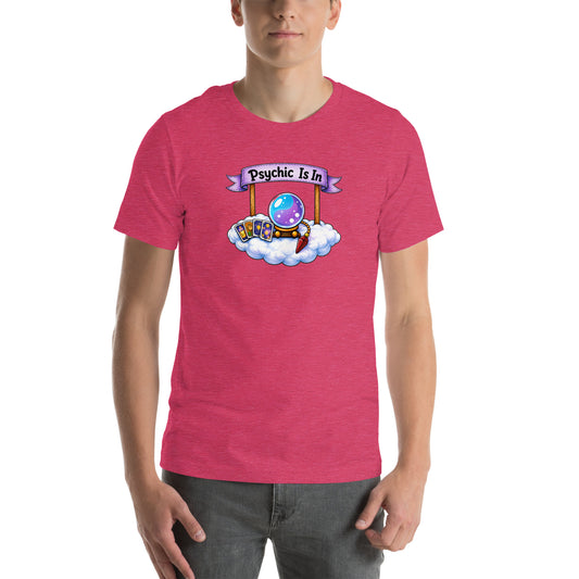 Psychic Is In design, playful floating clouds beneath a banner that reads Psychic Is Open for Business, on a heather raspberry unisex t-shirt, front view
