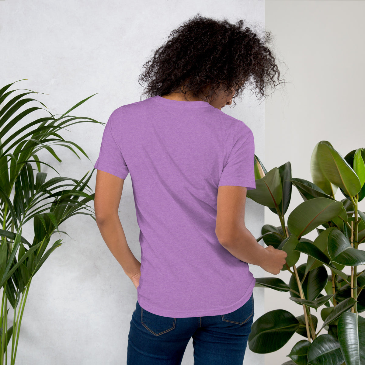 Booked and Bewitched dark academia design, a black cat asleep on a stack of spellbooks, on a heather team purple unisex t-shirt, back view