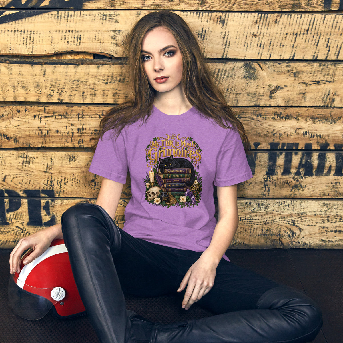 My TBR Is Mostly Grimoires dark academia design, a black cat guarding a stack of grimoires beside a skull, on a heather team purple unisex t-shirt, front view