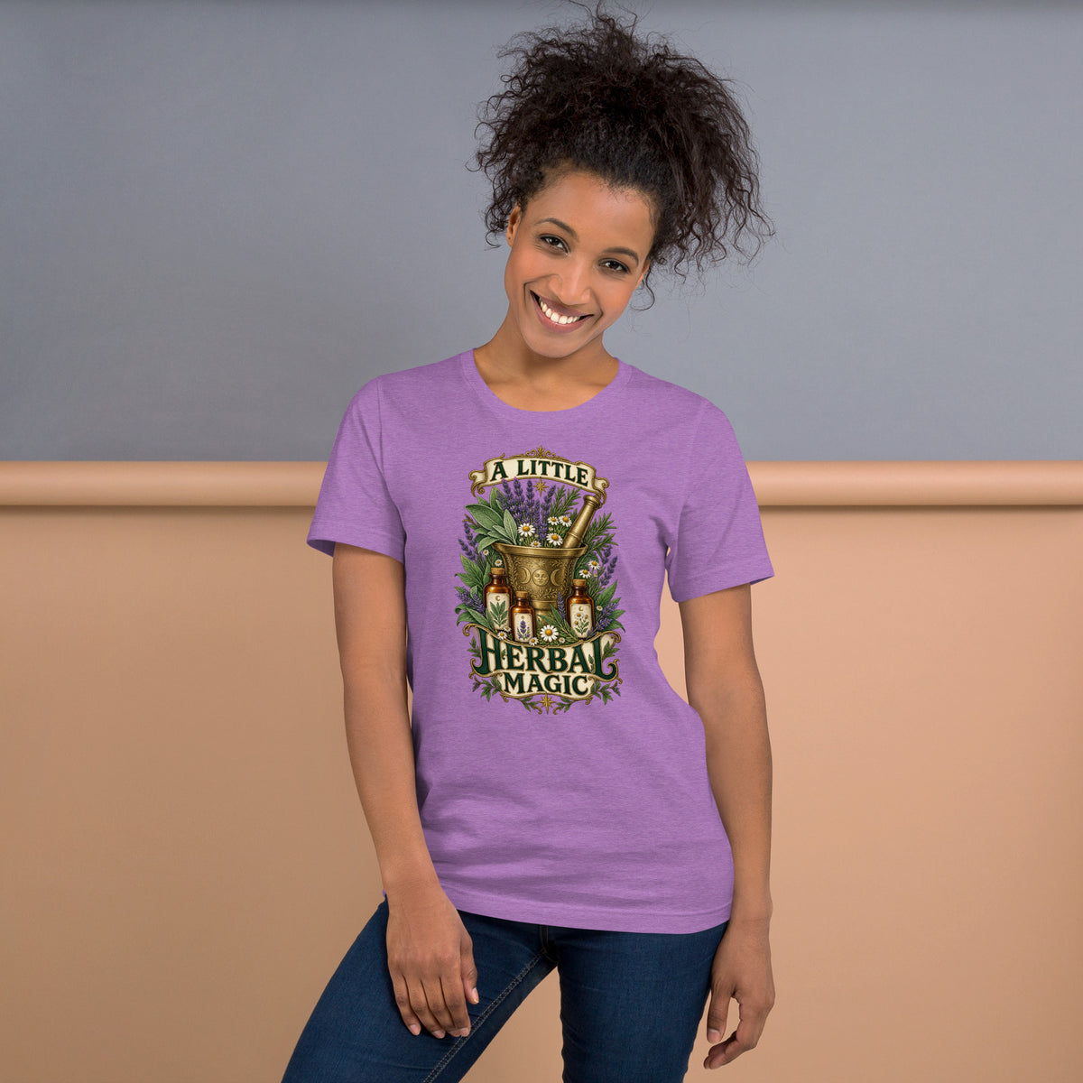 A Little Herbal Magic design, a gold mortar and pestle bearing a moon face, filled with lavender and chamomile and flanked by amber apothecary bottles, with the words on gold banners, on a heather team purple unisex t-shirt, front view