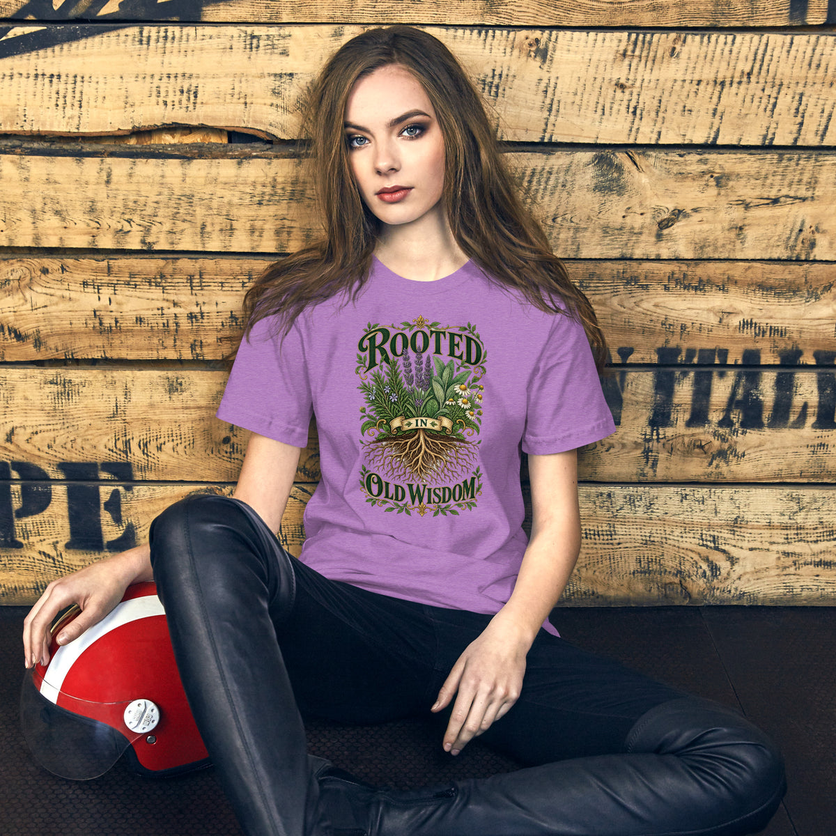 Rooted in Old Wisdom design, lavender, sage and chamomile growing above an exposed root system, with the words in dark green and gold inside a gold scrollwork border, on a heather team purple unisex t-shirt, front view