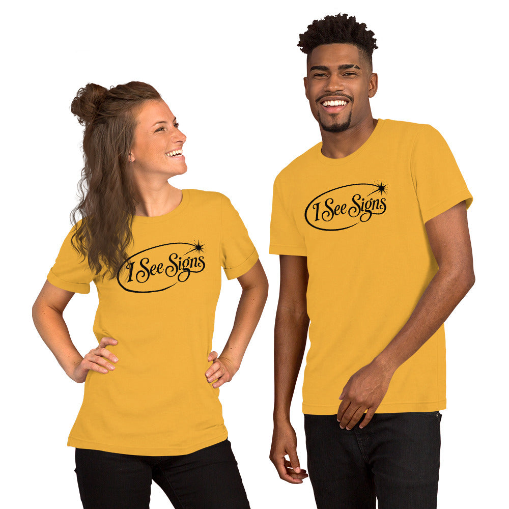I See Signs design, the words set in black script inside a thin oval with a four-pointed star, on a heather yellow gold unisex t-shirt, front view