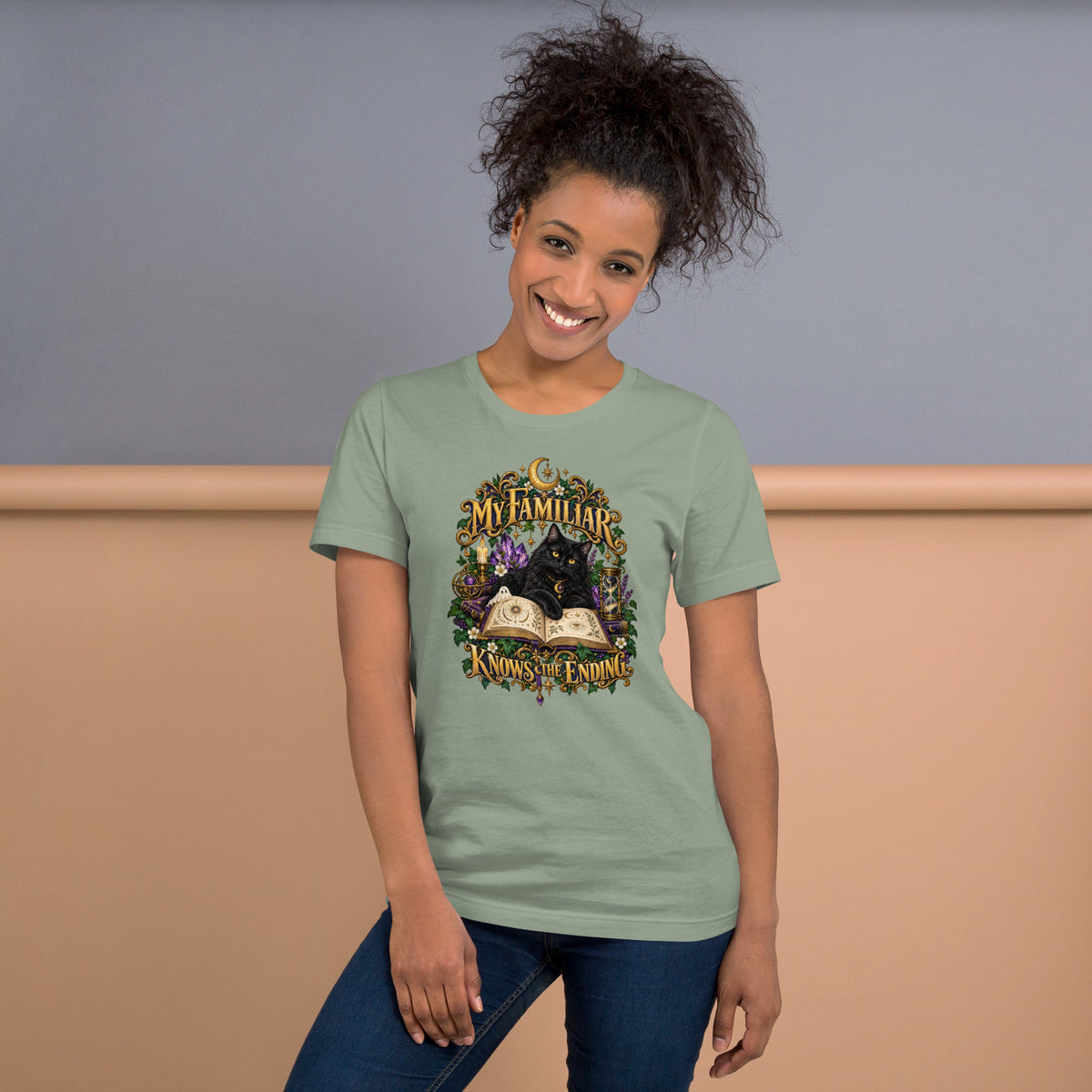 Black cat familiar on a grimoire, dark academia design on a sage unisex t-shirt, front view