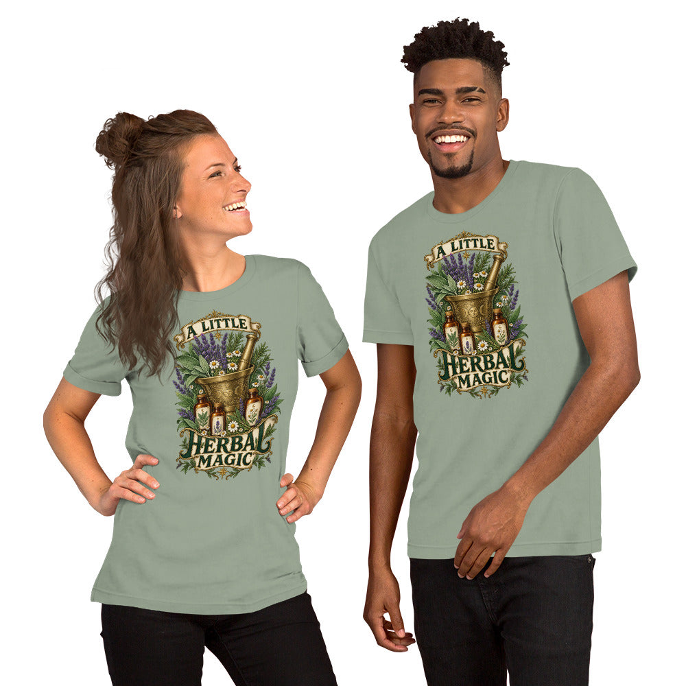 A Little Herbal Magic design, a gold mortar and pestle bearing a moon face, filled with lavender and chamomile and flanked by amber apothecary bottles, with the words on gold banners, on a sage unisex t-shirt, front view