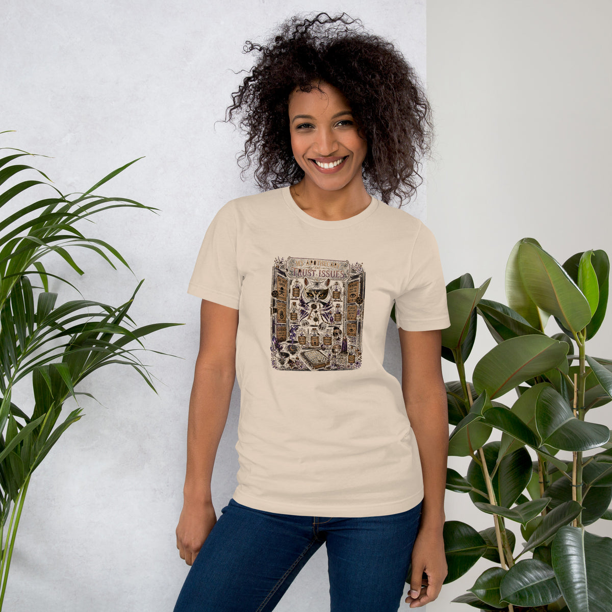 My Apothecary Has Trust Issues, a witchy black cat and a cabinet of potion bottles, on a soft cream unisex t-shirt, front view
