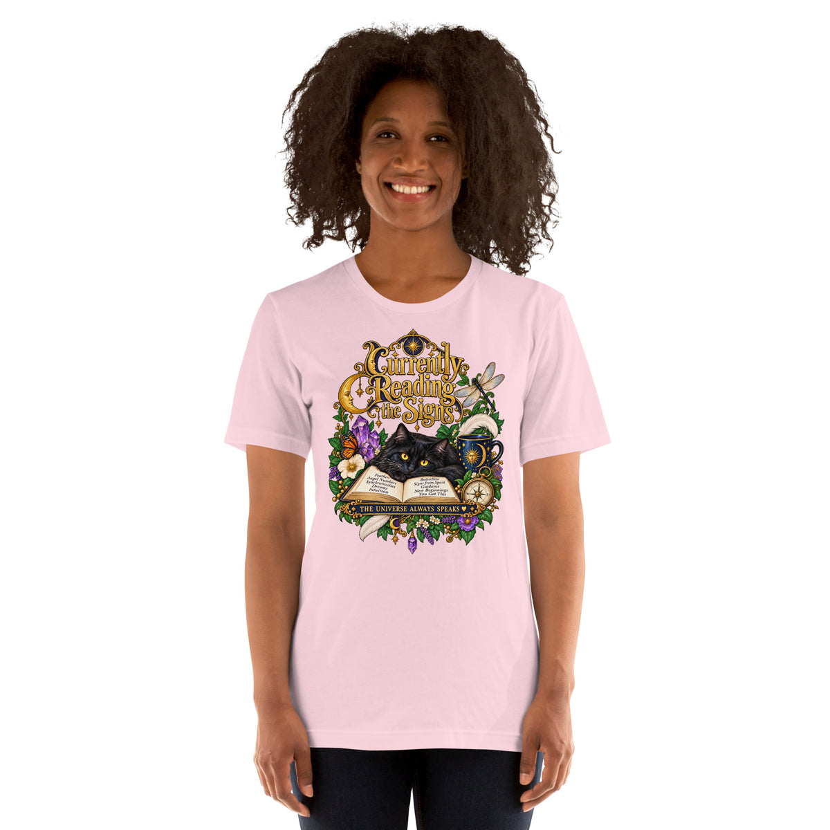 Currently Reading The Signs dark academia design, two black cats asleep over an open book beneath a crescent moon, on a soft pink unisex t-shirt, front view