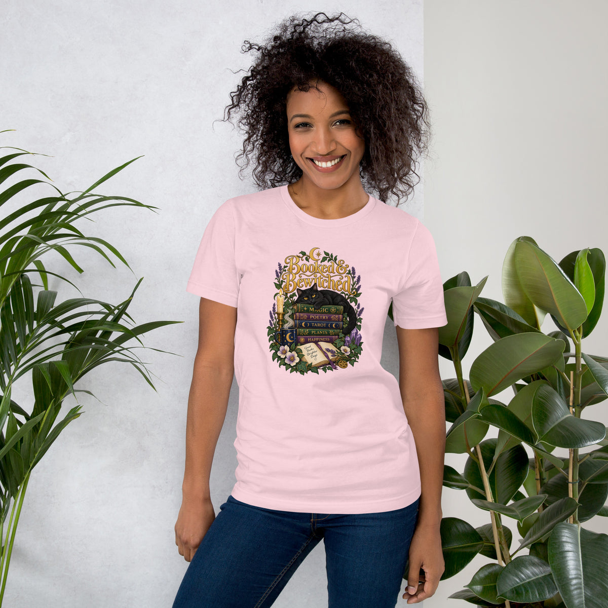 Booked and Bewitched dark academia design, a black cat asleep on a stack of spellbooks, on a soft pink unisex t-shirt, front view