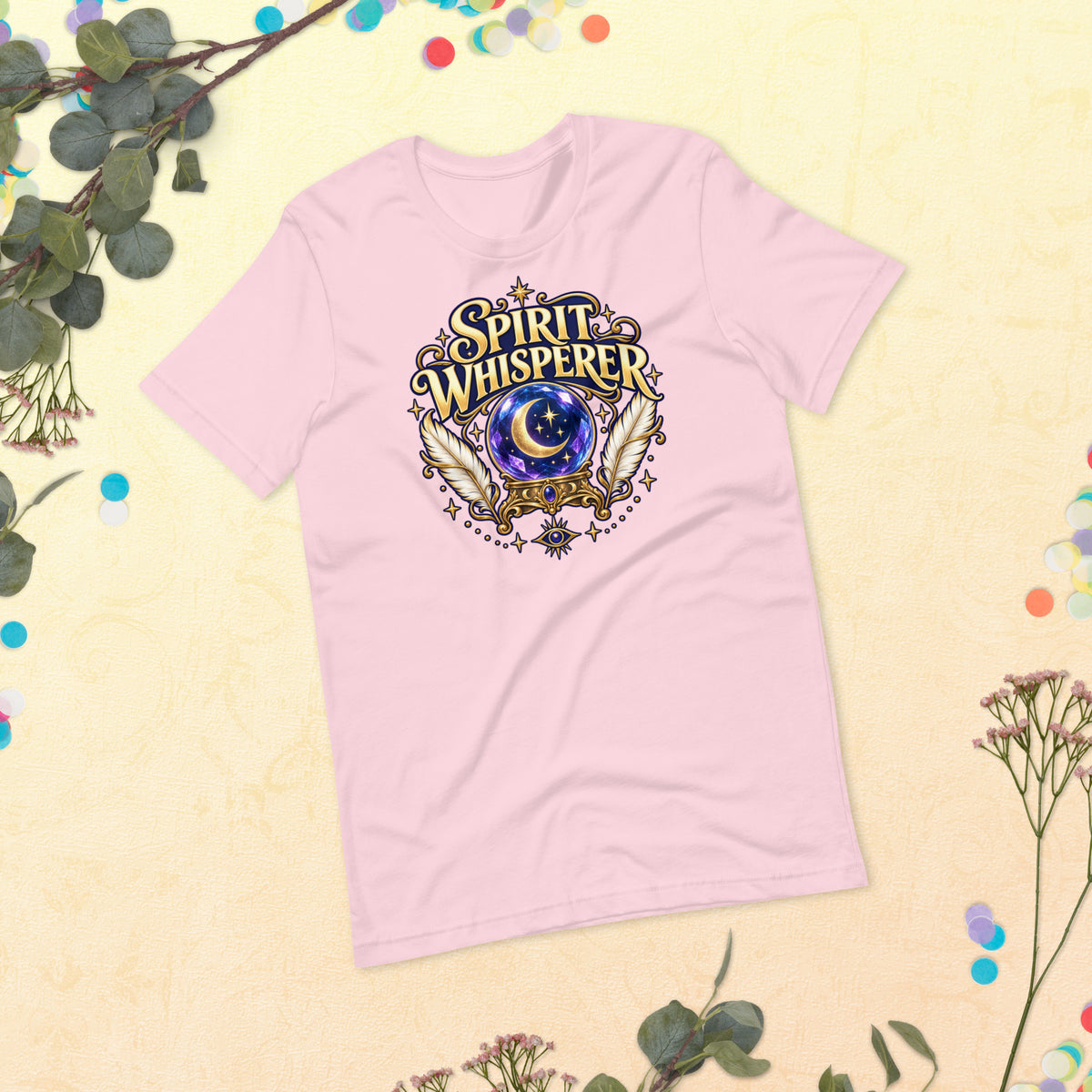 Spirit Whisperer unisex t-shirt in soft pink, front, laid flat. A crystal ball and feathers in a gold roundel.