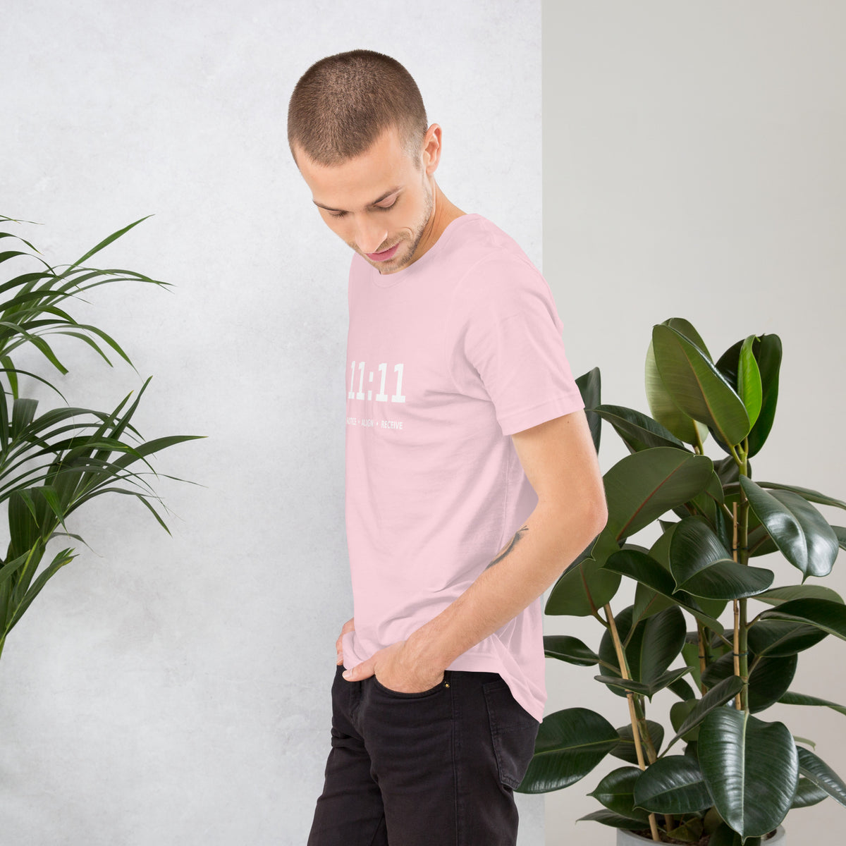 11:11 angel number design, the number set in plain white type above Notice, Align, Receive, on a soft pink unisex t-shirt, left side view