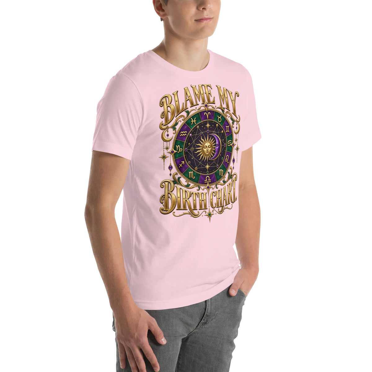 Blame My Birth Chart astrology design, a purple and green zodiac wheel with a gold sun face and crescent moon at its center, hung with gold ornaments, on a soft pink unisex t-shirt, angled right front view