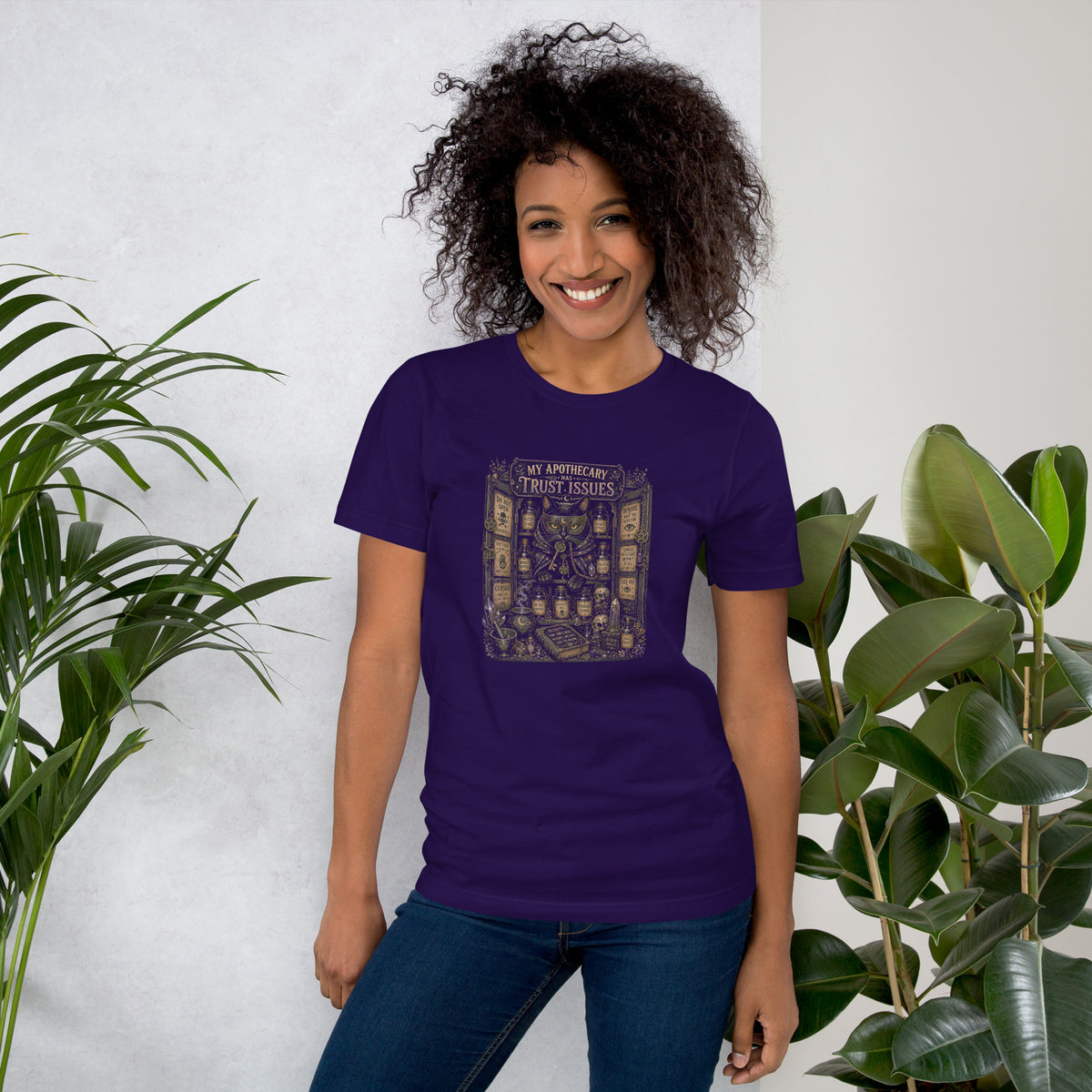My Apothecary Has Trust Issues, a witchy black cat and a cabinet of potion bottles, on a team purple unisex t-shirt, front view