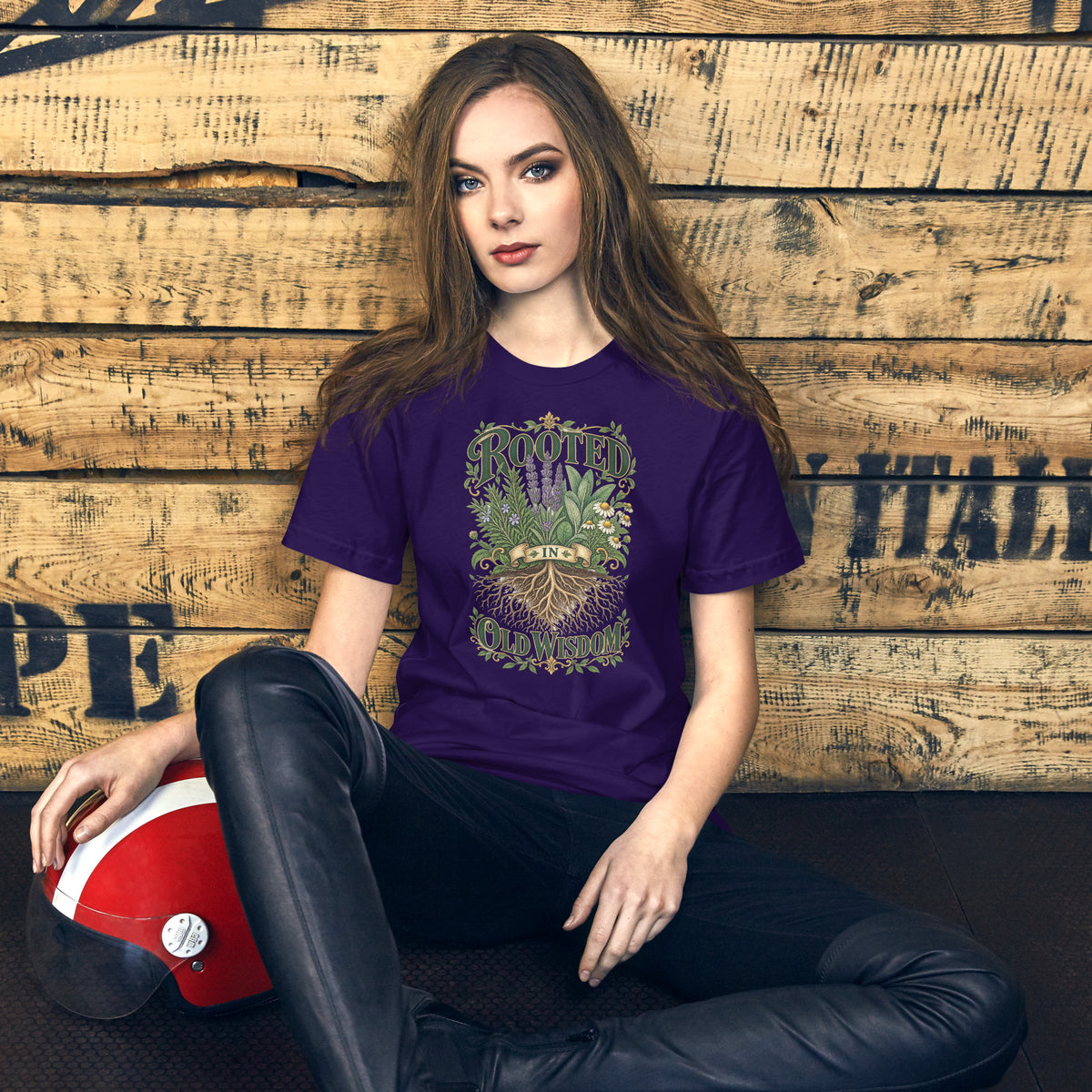 Rooted in Old Wisdom design, lavender, sage and chamomile growing above an exposed root system, with the words in dark green and gold inside a gold scrollwork border, on a team purple unisex t-shirt, front view