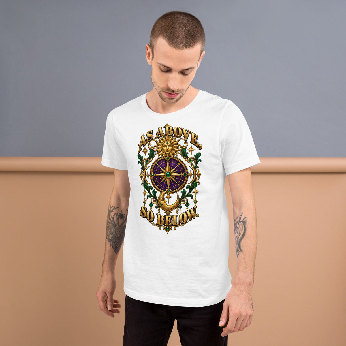 As Above, So Below astrology design, a gold sun face above a purple and gold compass rose with a crescent moon below, framed by emerald foliage, on a white unisex t-shirt, front view
