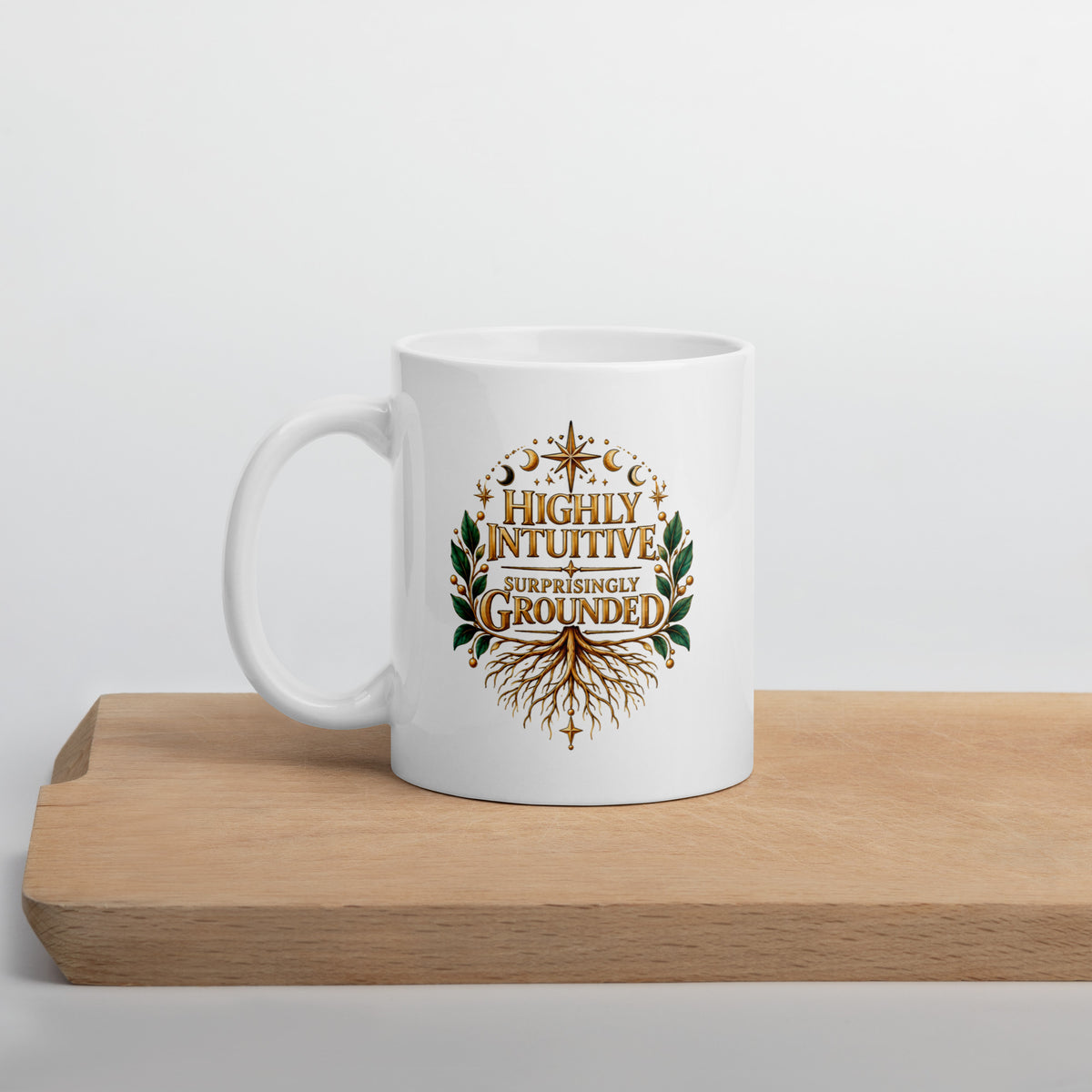 Highly Intuitive, Surprisingly Grounded design, moon phases above and roots below, on a white glossy mug, 11 oz, set on a wooden cutting board