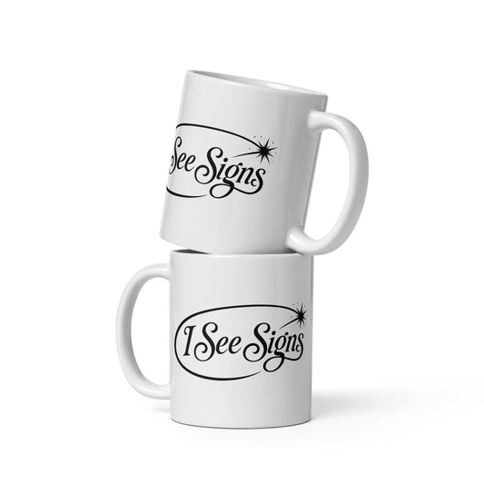 I See Signs design, the words set in black script inside a thin oval with a four-pointed star, on a white glossy mug, 11 oz, front view