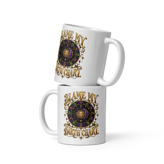Blame My Birth Chart astrology design, a purple and green zodiac wheel with a gold sun face and crescent moon at its center, hung with gold ornaments, on a 11 oz white glossy mug, front view