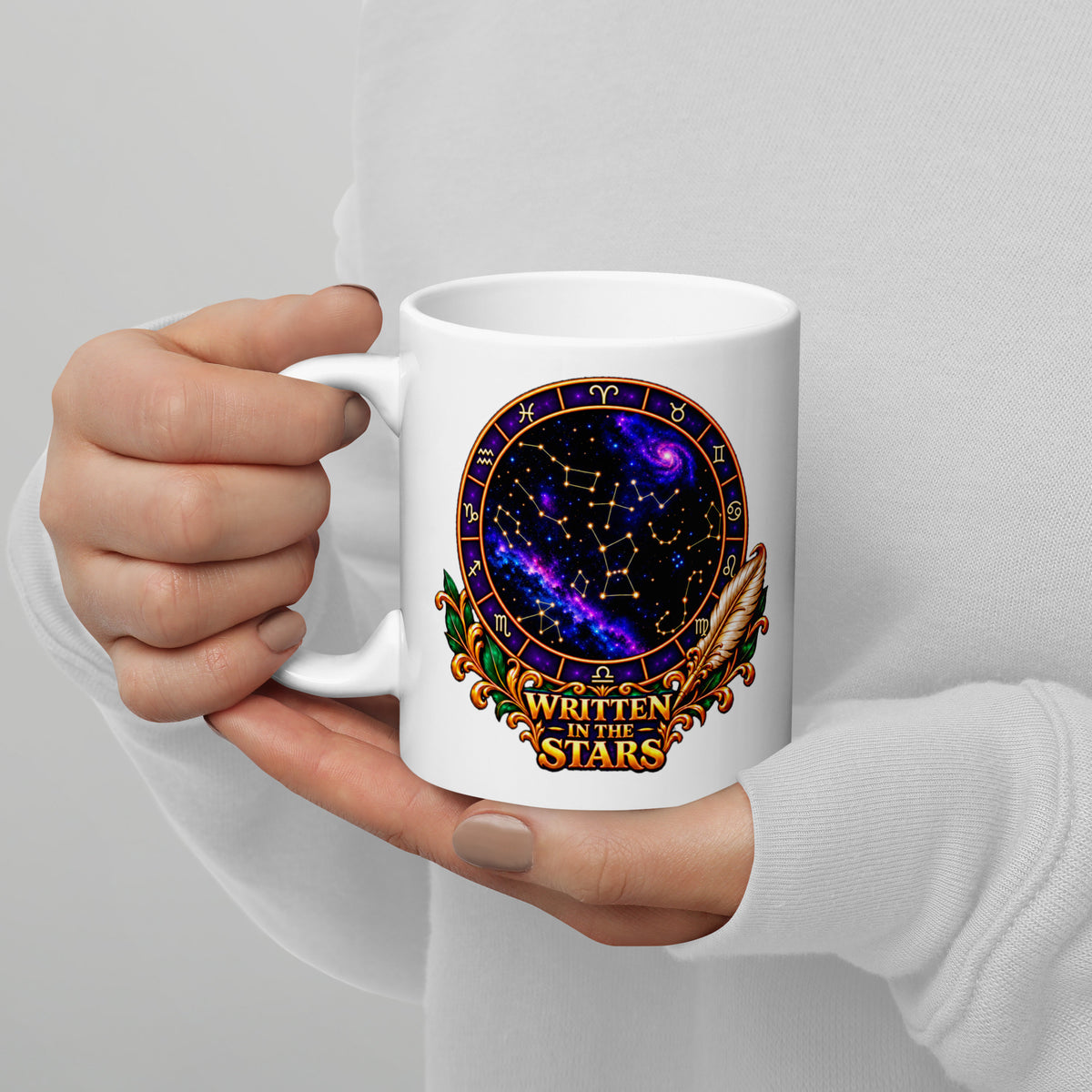Written In The Stars astrology design, a zodiac wheel of constellations and a galaxy framed by gold scrollwork and a feather quill, on a 11 oz white glossy mug, handle on the left