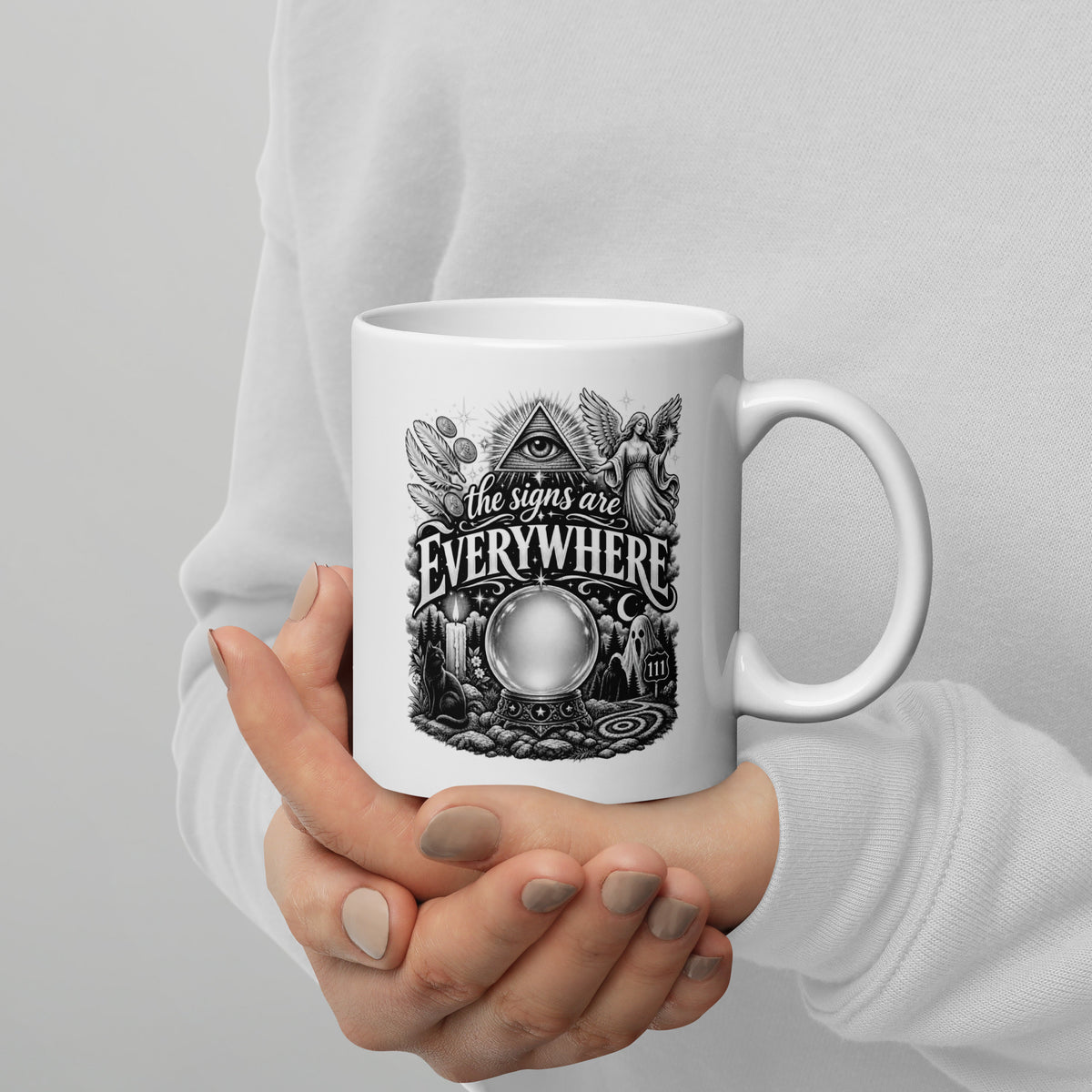The Signs Are Everywhere design, an all-seeing eye, an angel, a crystal ball, a black cat and a 111 road sign, in black and white line art, on a white glossy mug, 11 oz, handle on the right