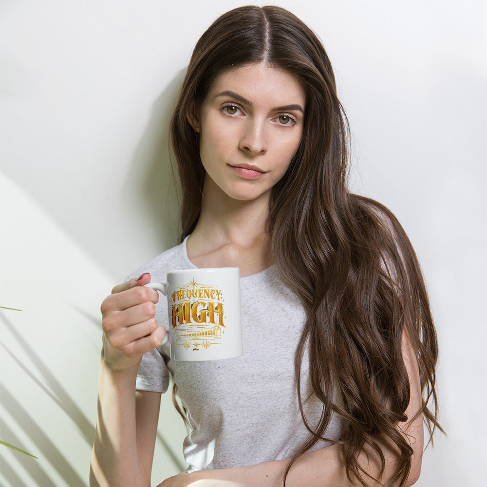 Frequency High design in gold, on a white glossy mug, 11 oz, held by a model