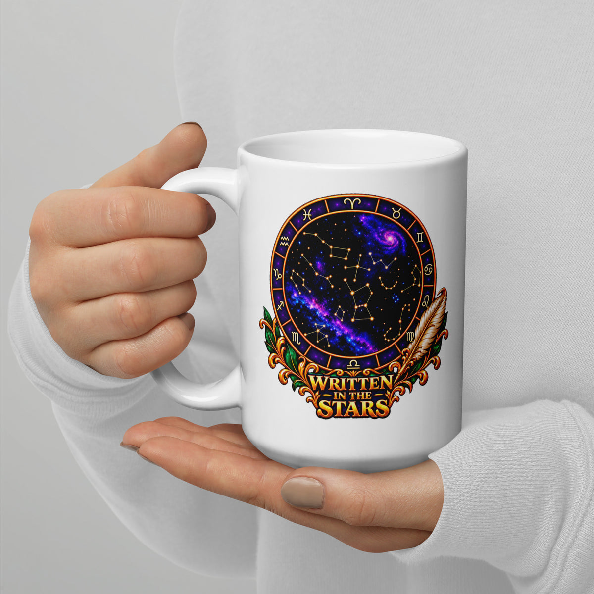 Written In The Stars astrology design, a zodiac wheel of constellations and a galaxy framed by gold scrollwork and a feather quill, on a 15 oz white glossy mug, handle on the left