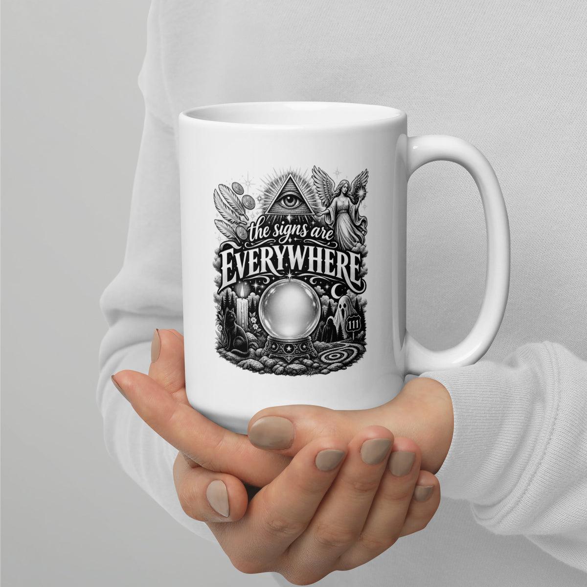 The Signs Are Everywhere design, an all-seeing eye, an angel, a crystal ball, a black cat and a 111 road sign, in black and white line art, on a white glossy mug, 15 oz, handle on the right