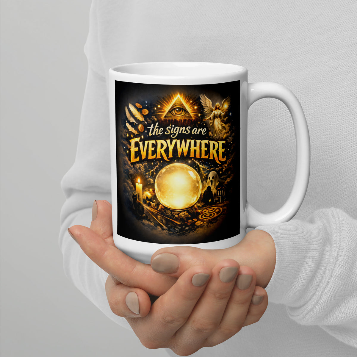 The Signs Are Everywhere design, an all-seeing eye, an angel, a glowing crystal ball, a ghost and a 111 road sign, in gold on black, on a white glossy mug, 15 oz, handle on the right