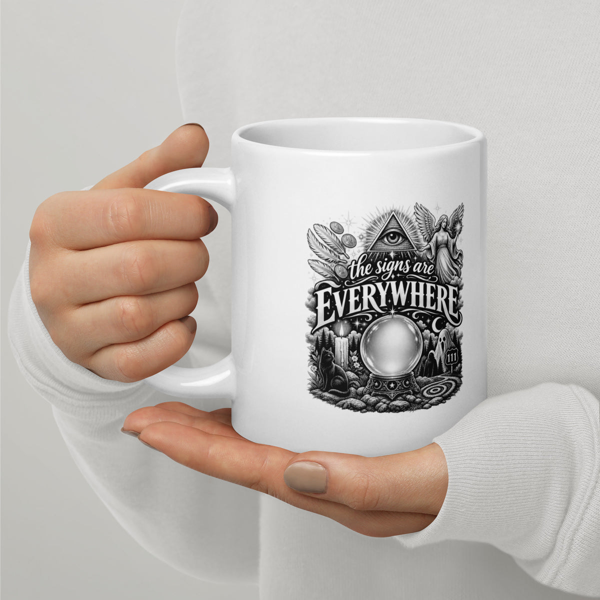 The Signs Are Everywhere design, an all-seeing eye, an angel, a crystal ball, a black cat and a 111 road sign, in black and white line art, on a white glossy mug, 20 oz, handle on the left