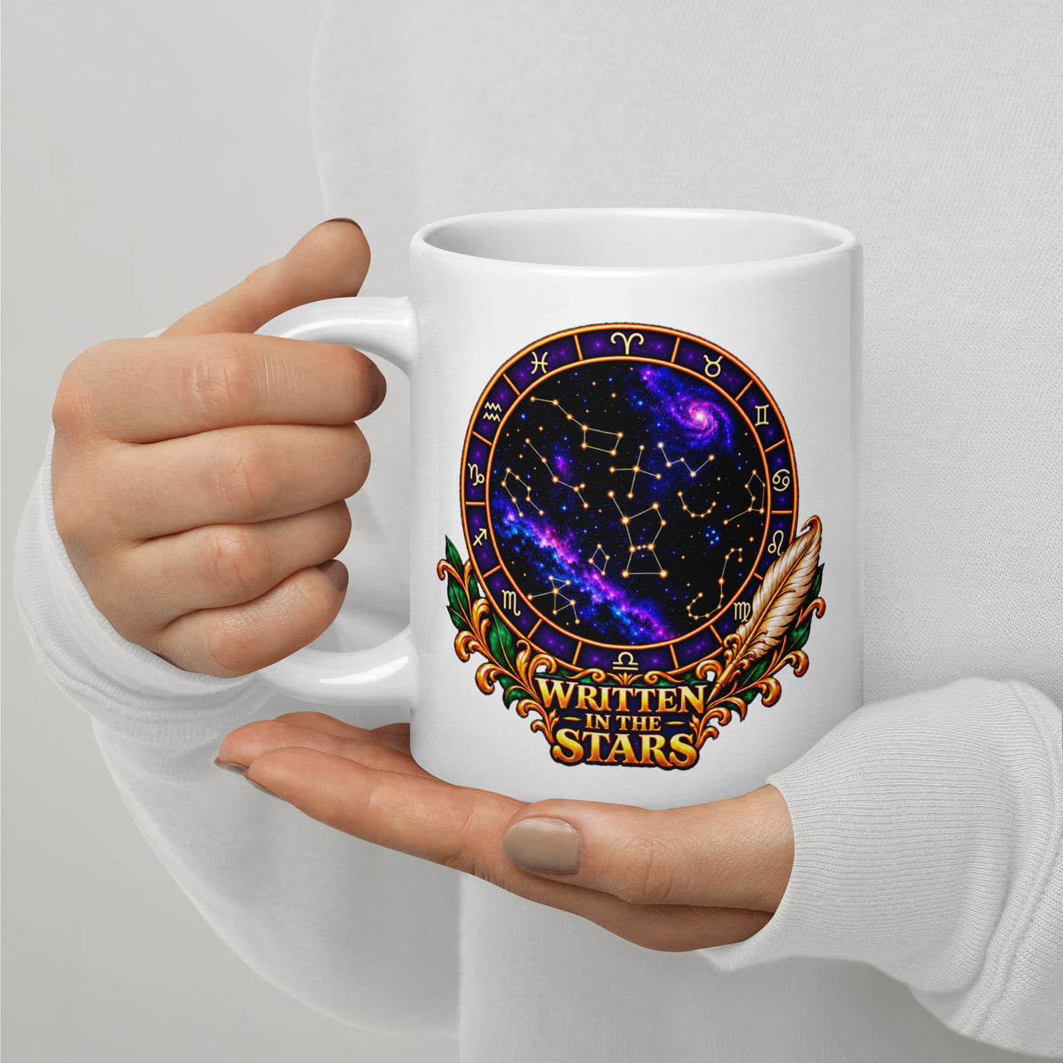 Written In The Stars astrology design, a zodiac wheel of constellations and a galaxy framed by gold scrollwork and a feather quill, on a 20 oz white glossy mug, handle on the left