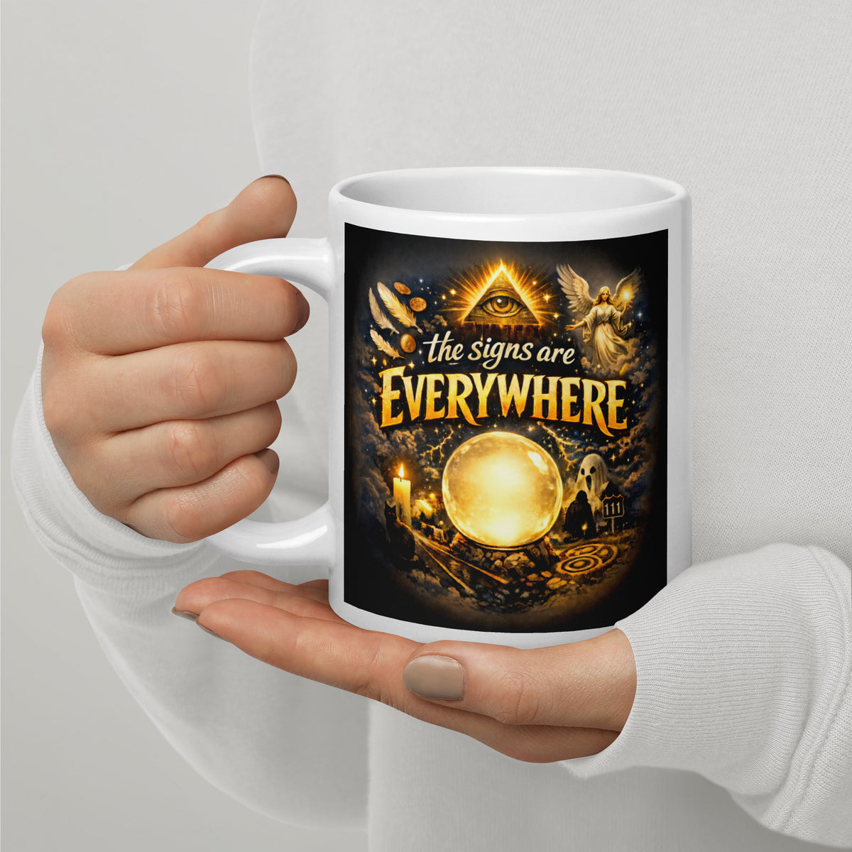 The Signs Are Everywhere design, an all-seeing eye, an angel, a glowing crystal ball, a ghost and a 111 road sign, in gold on black, on a white glossy mug, 20 oz, handle on the left