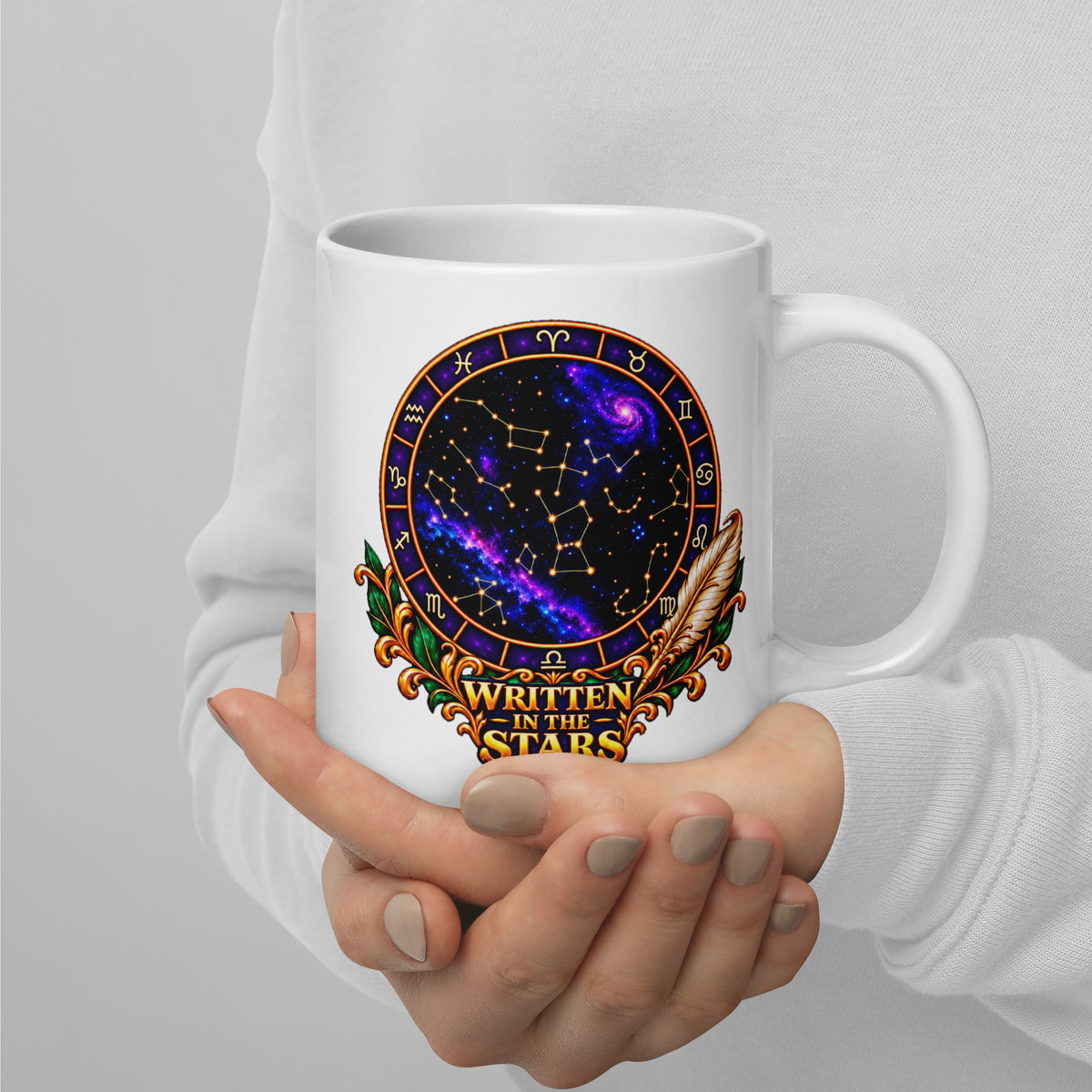 Written In The Stars astrology design, a zodiac wheel of constellations and a galaxy framed by gold scrollwork and a feather quill, on a 20 oz white glossy mug, handle on the right