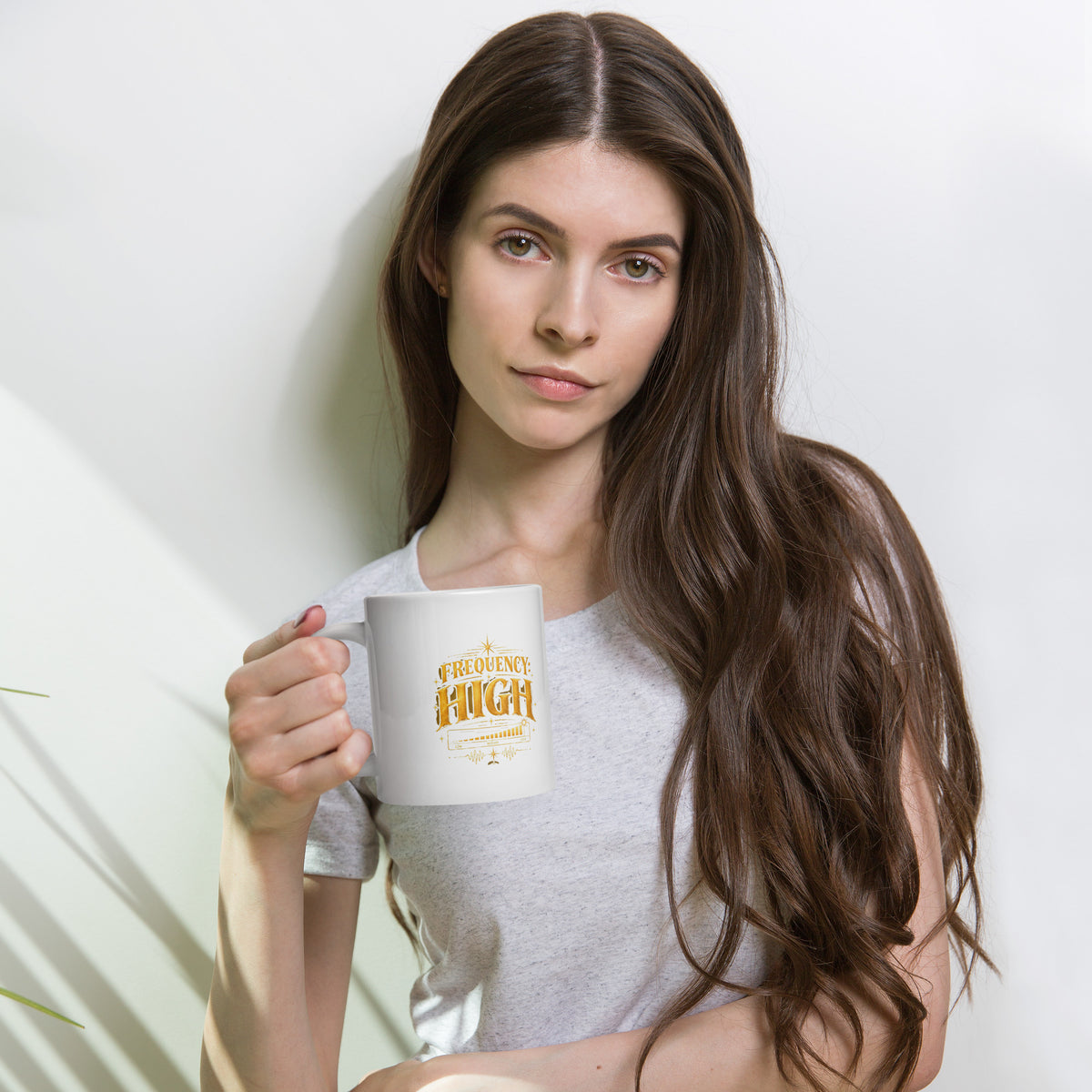 Frequency High design in gold, on a white glossy mug, 20 oz, held by a model