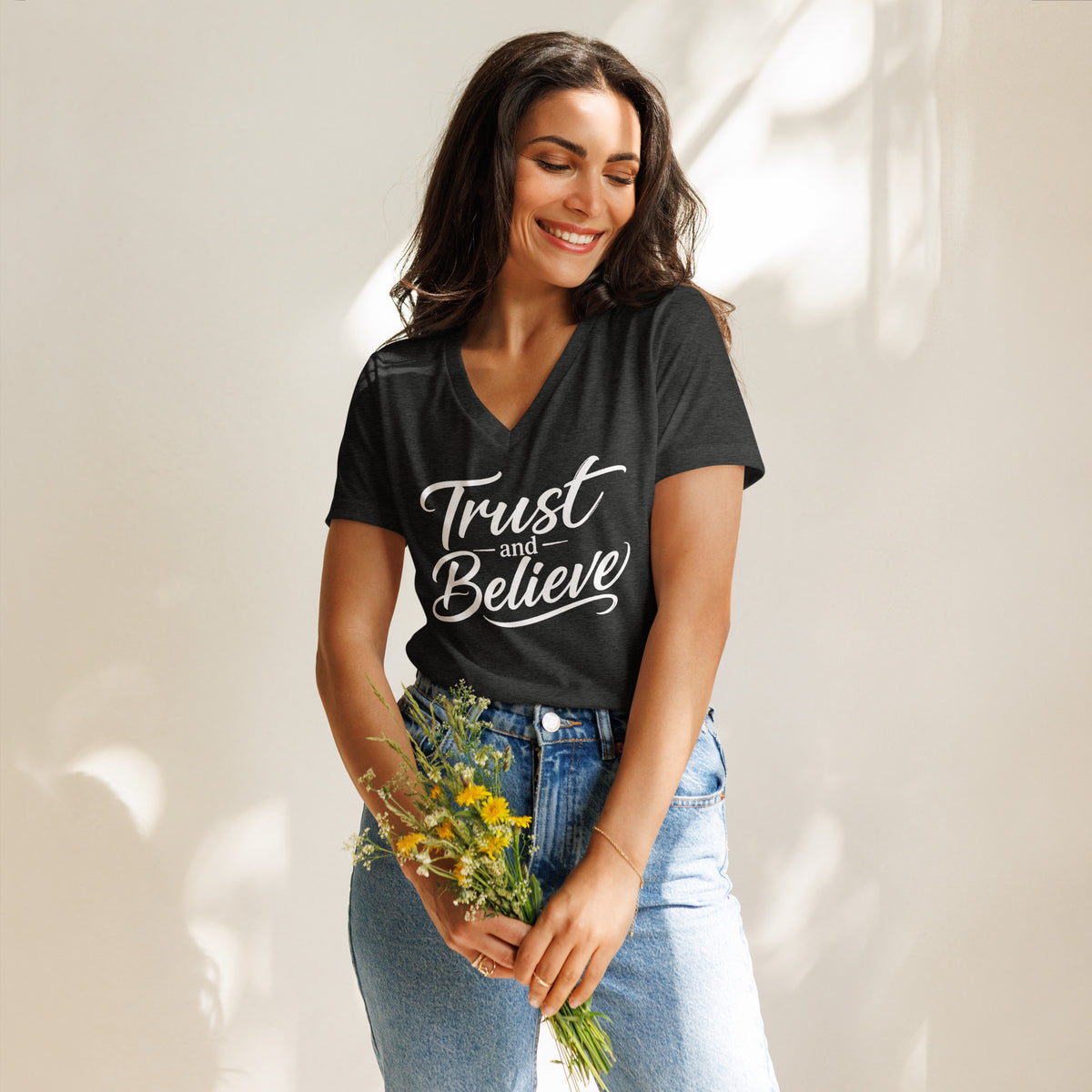 Trust and Believe design in white lettering, on a dark grey heather women's relaxed v-neck t-shirt, front view