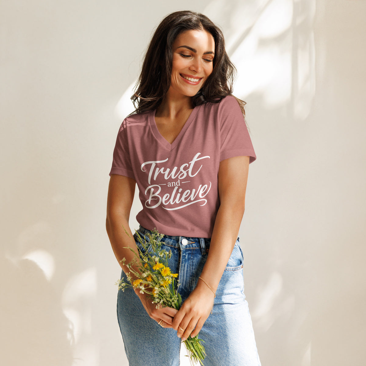 Trust and Believe design in white lettering, on a heather mauve women's relaxed v-neck t-shirt, front view