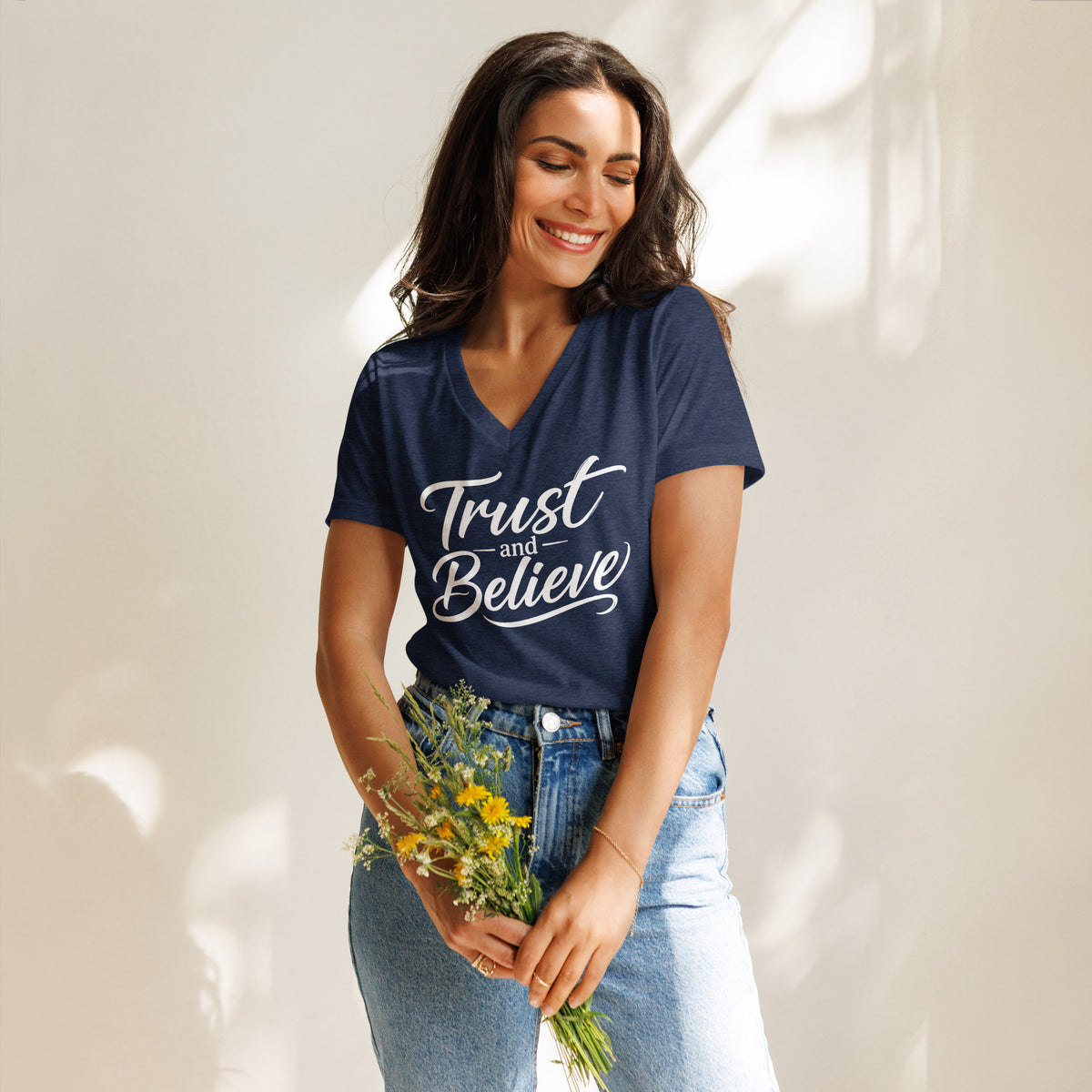 Trust and Believe design in white lettering, on a heather navy women's relaxed v-neck t-shirt, front view