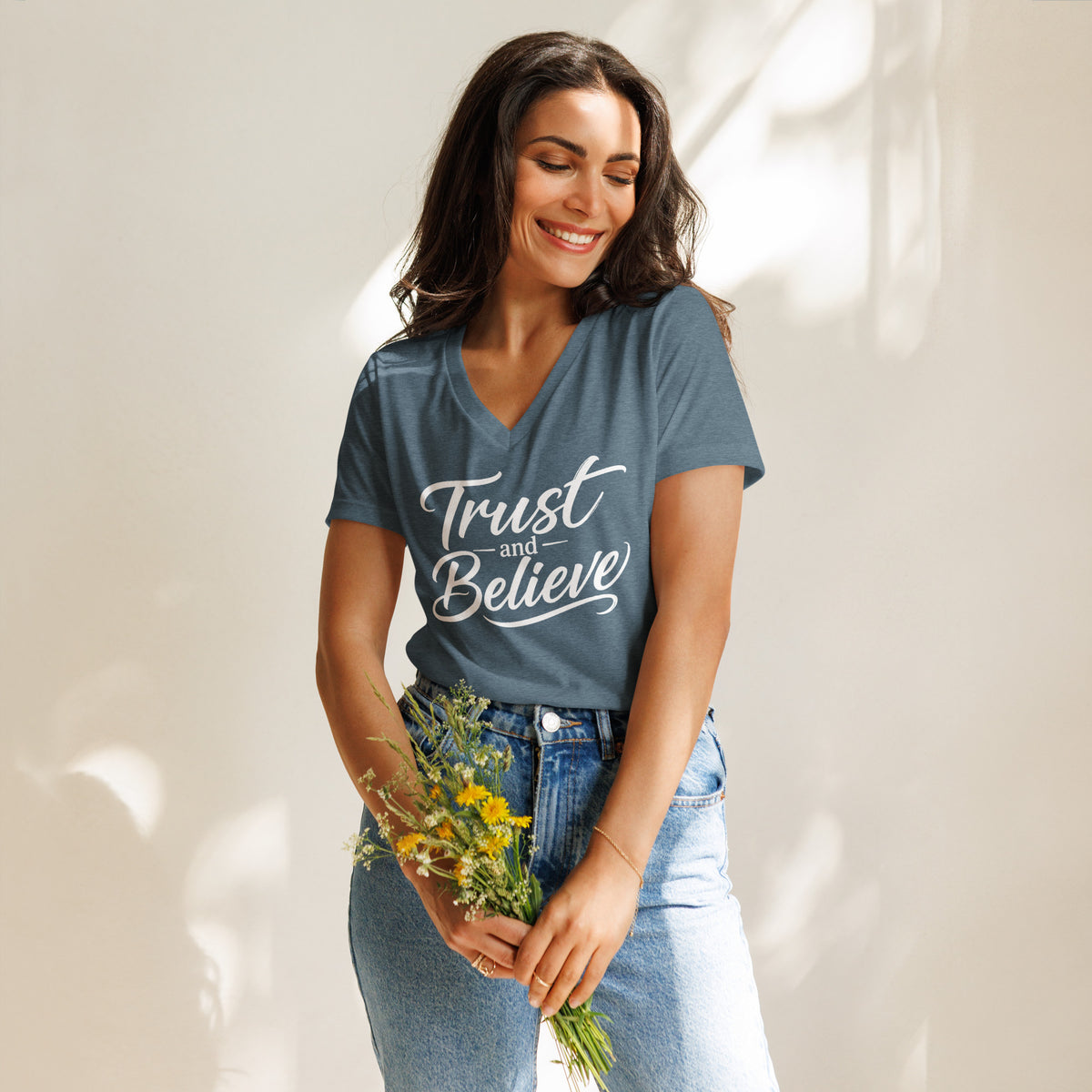 Trust and Believe design in white lettering, on a heather slate women's relaxed v-neck t-shirt, front view